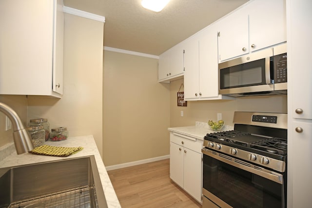 2855 Red Bud Ln, Anderson, CA 96007 - kitchen with stainless steel appliances, crown molding, light wood-type flooring, white cabinetry, and a textured ceiling