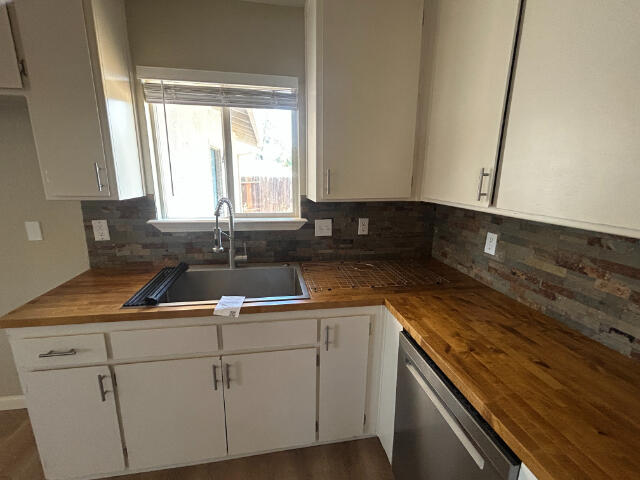 3995 Vassar Way, Shasta Lake, CA 96019 - kitchen with dishwasher, wooden counters, white cabinets, and tasteful backsplash