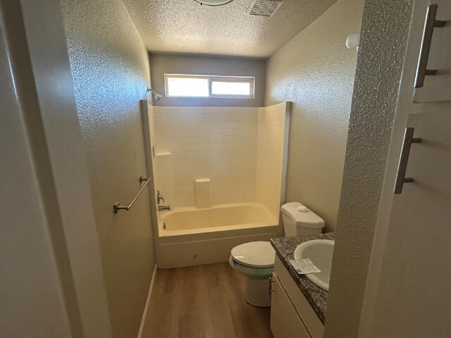 3995 Vassar Way, Shasta Lake, CA 96019 - bathroom featuring a textured ceiling, wood finished floors, vanity, a textured wall, and shower / washtub combination
