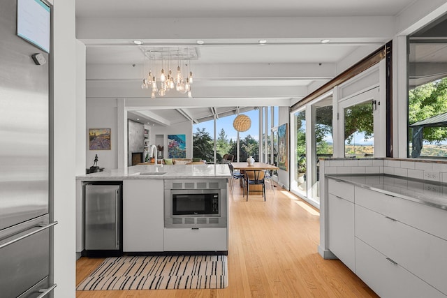 3540 Scenic Dr, Redding, CA 96001 - kitchen with stainless steel appliances, light wood-type flooring, white cabinets, beamed ceiling, and beverage cooler