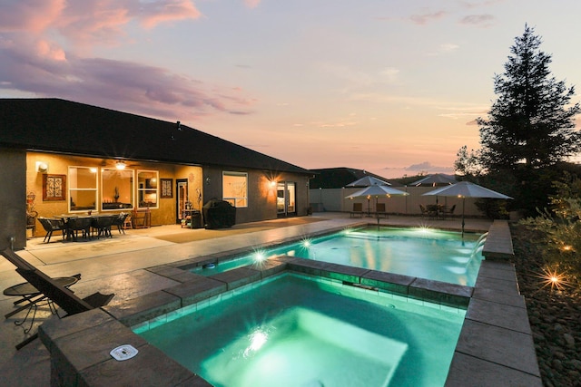 4075 Pembroke Ln, Shasta Lake, CA 96019 - pool at dusk featuring an in-ground hot tub, a patio, and outdoor dining space