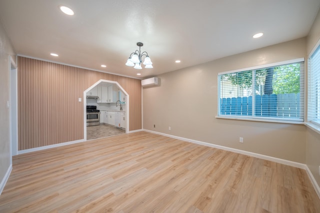 4725 Cedars Rd, Redding, CA 96001 - spare room with arched walkways, an AC wall unit, a chandelier, recessed lighting, and light wood-style flooring