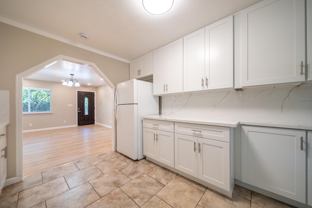 4725 Cedars Rd, Redding, CA 96001 - kitchen with freestanding refrigerator, a chandelier, white cabinets, backsplash, and light stone countertops
