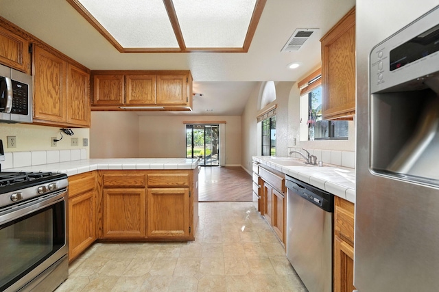 2585 Meadowview Dr, Red Bluff, CA 96080 - kitchen featuring appliances with stainless steel finishes, tile countertops, a peninsula, and brown cabinets