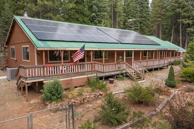 36088 Deer Flat Rd, Shingletown, CA 96088 - chalet / cabin featuring covered porch, a wooded view, a metal roof, solar panels, and a gate