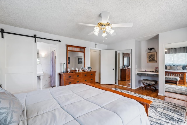 14480 Warren Ave, Red Bluff, CA 96080 - bedroom with wood finished floors, a barn door, a textured ceiling, ensuite bath, and ceiling fan