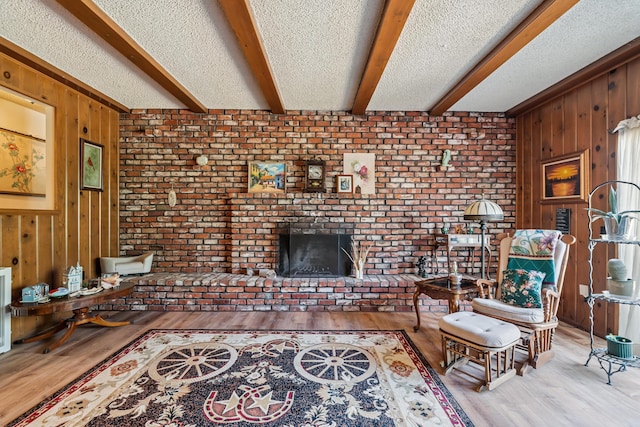14480 Warren Ave, Red Bluff, CA 96080 - living area featuring wood walls, beam ceiling, wood finished floors, a brick fireplace, and a textured ceiling
