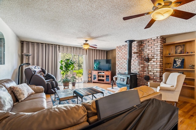 14480 Warren Ave, Red Bluff, CA 96080 - living room featuring a ceiling fan, a wood stove, wood finished floors, and a textured ceiling