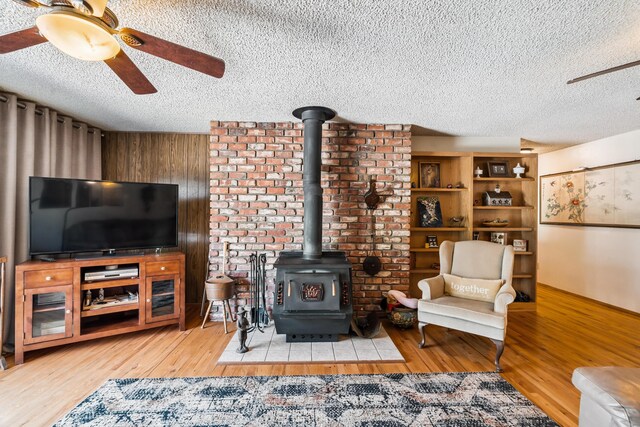 14480 Warren Ave, Red Bluff, CA 96080 - living room featuring ceiling fan, a textured ceiling, a wood stove, and wood finished floors
