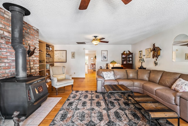 14480 Warren Ave, Red Bluff, CA 96080 - living room featuring ceiling fan, a wood stove, light wood-type flooring, and a textured ceiling