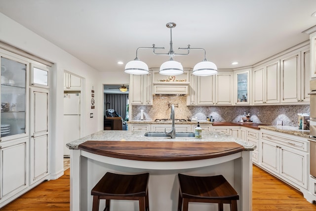 14480 Warren Ave, Red Bluff, CA 96080 - kitchen with freestanding refrigerator, light wood finished floors, backsplash, a center island with sink, and recessed lighting
