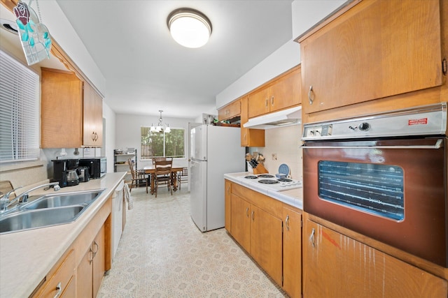 4215 Oro St, Redding, CA 96002 - kitchen with white appliances, under cabinet range hood, light countertops, light flooring, and a chandelier