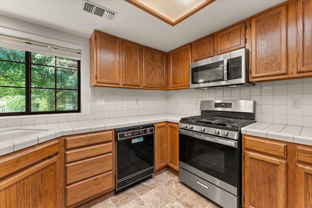 3628 Somerset Ave, Redding, CA 96002 - kitchen featuring stainless steel appliances, tasteful backsplash, and brown cabinets