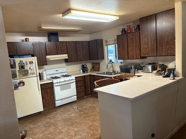20194 Sugar Pine St, Burney, CA 96013 - kitchen with white appliances, under cabinet range hood, a textured ceiling, a peninsula, and light countertops