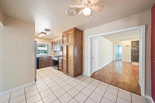 3255 Winding Way, Redding, CA 96003 - kitchen with black appliances, light tile patterned floors, a ceiling fan, brown cabinets, and light countertops