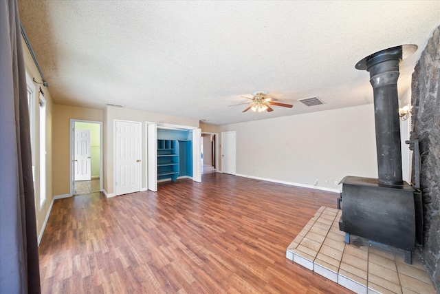 3255 Winding Way, Redding, CA 96003 - unfurnished living room featuring a wood stove, wood finished floors, ceiling fan, and a textured ceiling