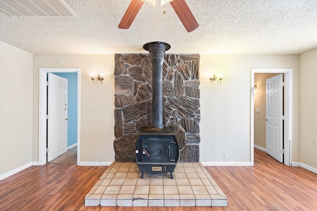 3255 Winding Way, Redding, CA 96003 - detailed view of a wood stove, wood finished floors, a textured ceiling, and a ceiling fan
