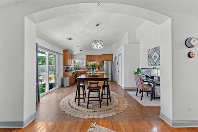 2236 Lonigan Ct, Redding, CA 96001 - dining area featuring a chandelier, wood-type flooring, vaulted ceiling, and arched walkways