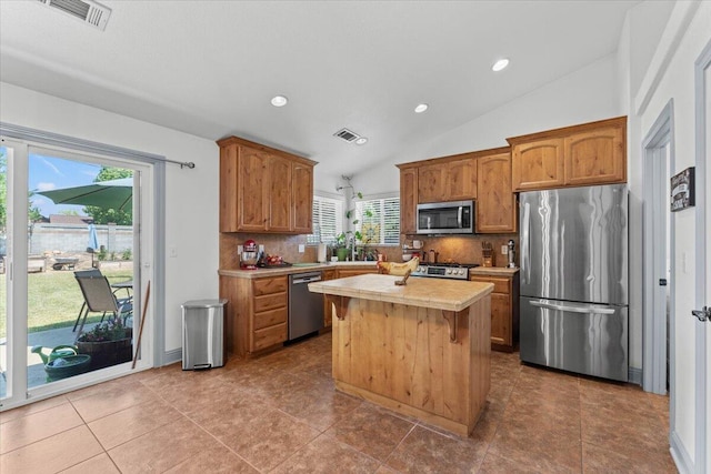2236 Lonigan Ct, Redding, CA 96001 - kitchen featuring appliances with stainless steel finishes, backsplash, light countertops, a center island, and lofted ceiling
