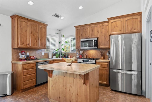 2236 Lonigan Ct, Redding, CA 96001 - kitchen with stainless steel appliances, a center island, vaulted ceiling, decorative backsplash, and tile countertops
