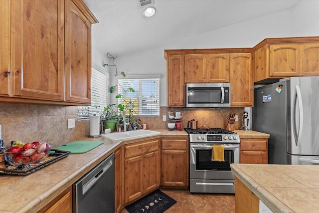 2236 Lonigan Ct, Redding, CA 96001 - kitchen featuring appliances with stainless steel finishes, lofted ceiling, backsplash, and brown cabinetry