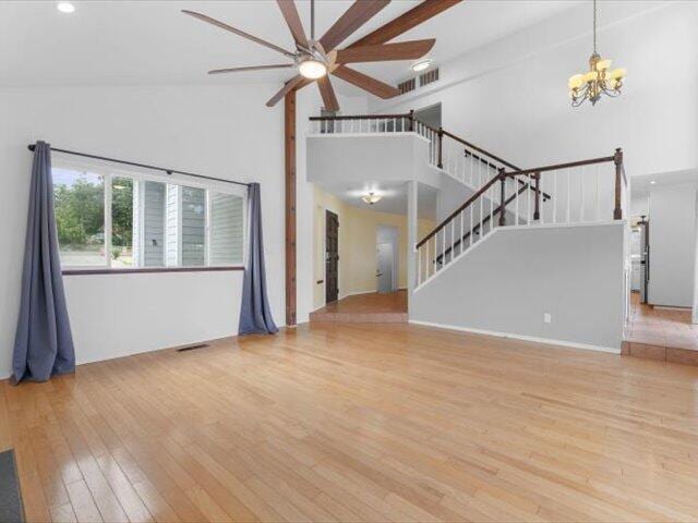 15540 China Rapids Dr, Red Bluff, CA 96080 - unfurnished living room with high vaulted ceiling, a ceiling fan, a chandelier, wood finished floors, and stairs
