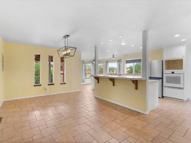 15540 China Rapids Dr, Red Bluff, CA 96080 - kitchen with white oven, freestanding refrigerator, a kitchen breakfast bar, a chandelier, and open floor plan