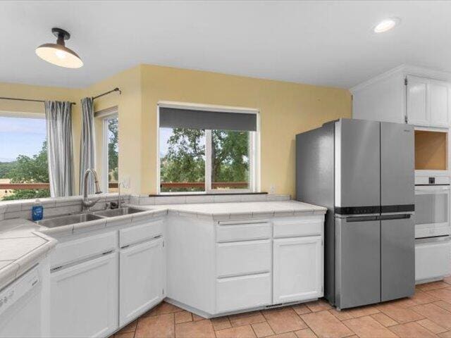 15540 China Rapids Dr, Red Bluff, CA 96080 - kitchen with white appliances, tile countertops, healthy amount of natural light, and white cabinets
