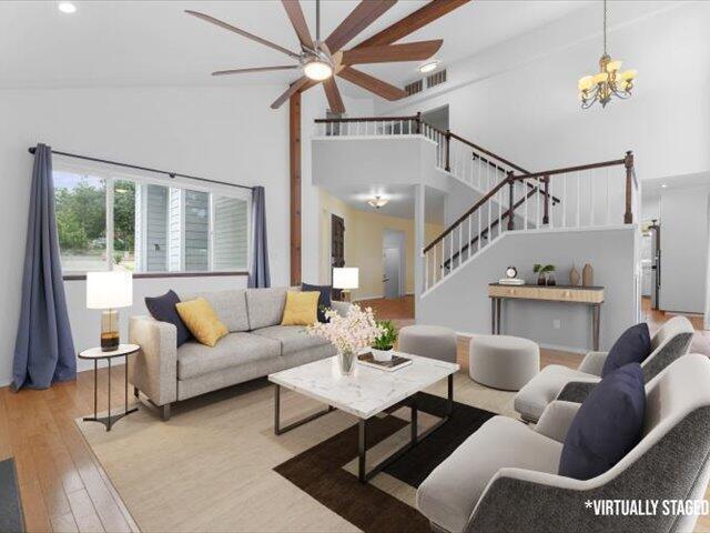 15540 China Rapids Dr, Red Bluff, CA 96080 - living room featuring a towering ceiling, ceiling fan, stairs, hardwood / wood-style flooring, and a chandelier