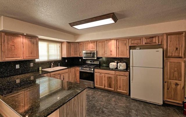 21657 W Elk Trl, Redding, CA 96003 - kitchen featuring stainless steel appliances, a peninsula, decorative backsplash, a textured ceiling, and dark stone counters