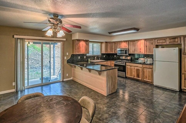 21657 W Elk Trl, Redding, CA 96003 - kitchen featuring appliances with stainless steel finishes, a peninsula, dark countertops, ceiling fan, and a textured ceiling