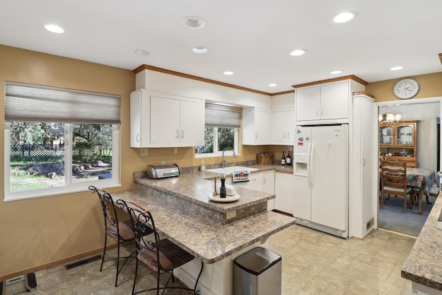 3283 Middleton Ln, Redding, CA 96002 - kitchen featuring white fridge with ice dispenser, a peninsula, recessed lighting, white cabinetry, and stone finish flooring