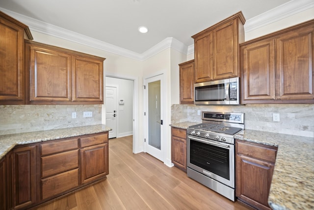 5569 Diamond Ridge Dr, Redding, CA 96003 - kitchen featuring appliances with stainless steel finishes, ornamental molding, backsplash, light wood finished floors, and light stone countertops