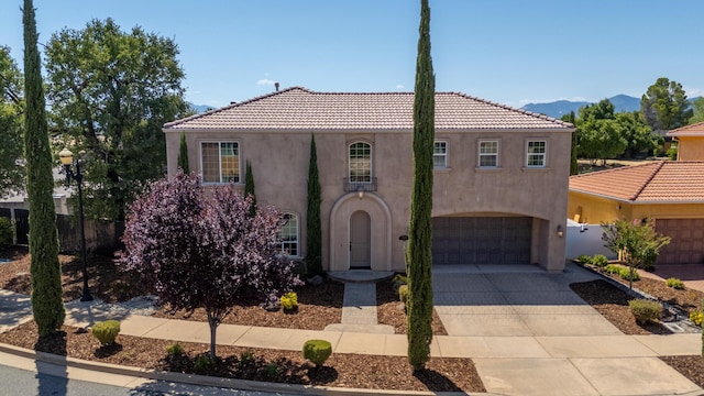 5569 Diamond Ridge Dr, Redding, CA 96003 - mediterranean / spanish-style house with stucco siding, concrete driveway, a garage, a mountain view, and a tiled roof
