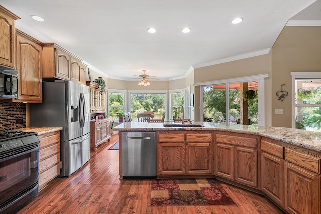 1533 Spanish Bay Dr, Redding, CA 96003 - kitchen with appliances with stainless steel finishes, ornamental molding, healthy amount of natural light, dark wood-style flooring, and light stone countertops