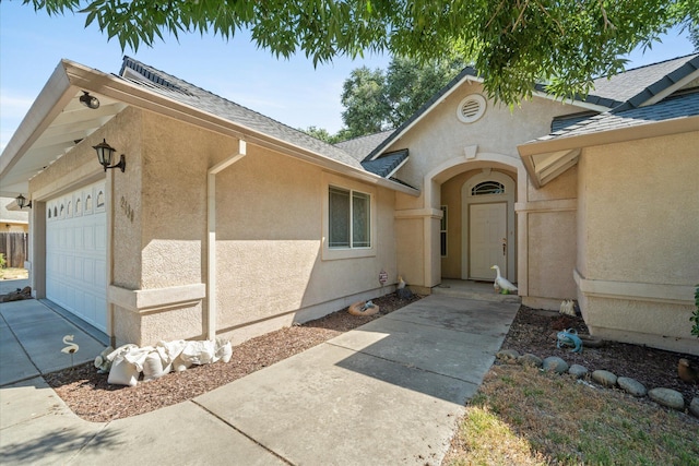 2790 Citrine Ave, Redding, CA 96001 - property entrance featuring stucco siding, an attached garage, a shingled roof, and concrete driveway