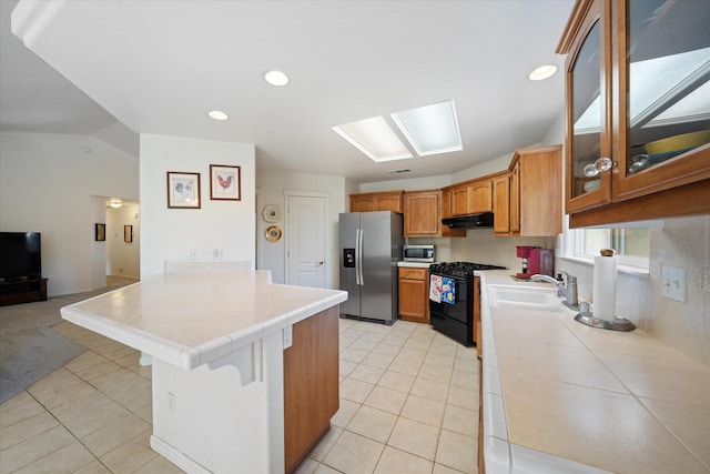 2790 Citrine Ave, Redding, CA 96001 - kitchen featuring appliances with stainless steel finishes, a peninsula, tile countertops, light tile patterned flooring, and vaulted ceiling