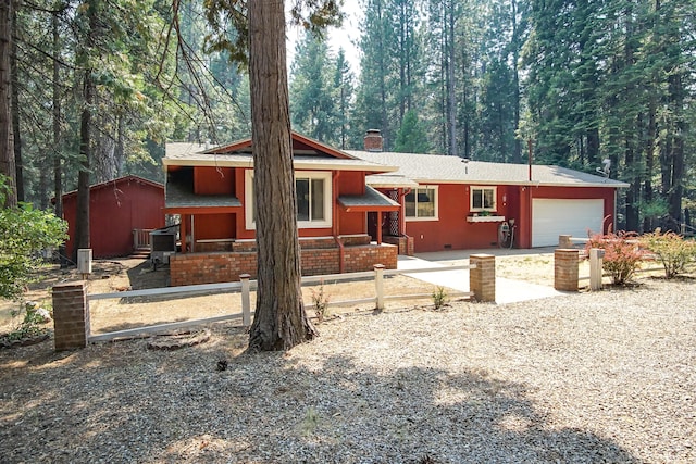 30839 Tinkerbell Ln, Shingletown, CA 96088 - view of front facade with a chimney, an attached garage, a forest view, driveway, and roof with shingles