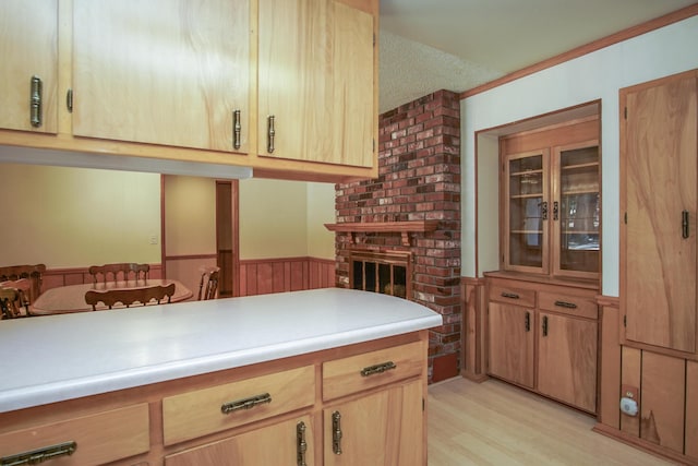 30839 Tinkerbell Ln, Shingletown, CA 96088 - kitchen featuring light wood-style floors, light countertops, a brick fireplace, wainscoting, and light brown cabinets