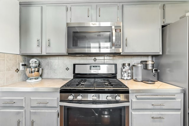4020 Oro St, Redding, CA 96001 - kitchen featuring appliances with stainless steel finishes, light countertops, decorative backsplash, and gray cabinetry
