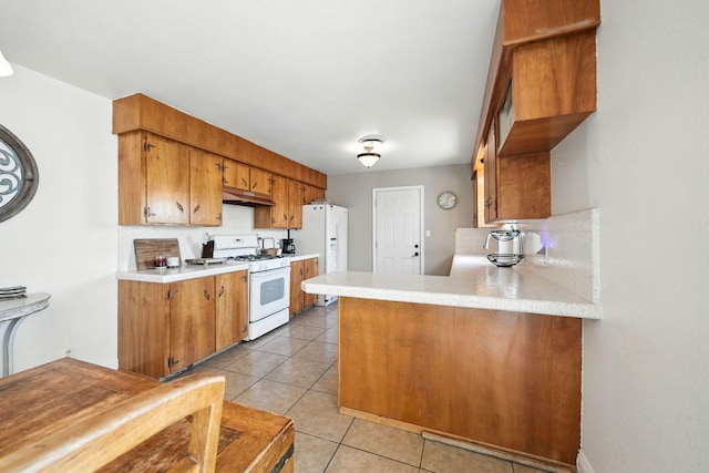 2045 Washington Ave, Red Bluff, CA 96080 - kitchen with white appliances, under cabinet range hood, light countertops, a peninsula, and brown cabinets
