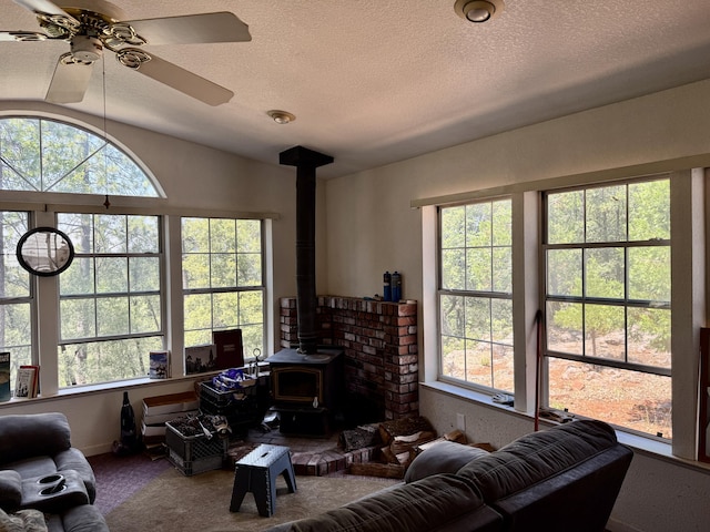 11941 Atkins Rd, Whitmore, CA 96096 - carpeted living area featuring a wood stove, plenty of natural light, a ceiling fan, a textured ceiling, and vaulted ceiling