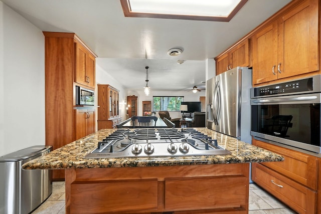 24470 Oklahoma Ave, Red Bluff, CA 96080 - kitchen with stainless steel appliances, brown cabinets, a kitchen island, open floor plan, and dark stone countertops