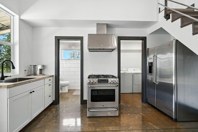 23795 Deer Canyon Rd, Millville, CA 96062 - kitchen with appliances with stainless steel finishes, wall chimney range hood, washer and clothes dryer, white cabinetry, and finished concrete floors