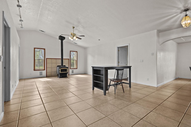 12526 Glide Way, Redding, CA 96003 - living area with vaulted ceiling, a textured ceiling, a ceiling fan, light tile patterned floors, and a wood stove