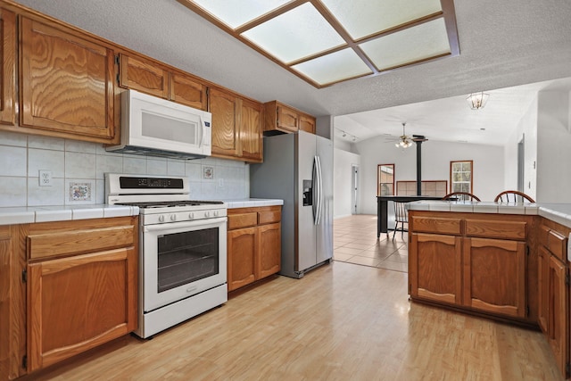 12526 Glide Way, Redding, CA 96003 - kitchen featuring white appliances, vaulted ceiling, backsplash, brown cabinets, and a ceiling fan