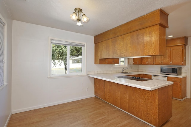 210 Sherman St, Yreka, CA 96097 - kitchen with stainless steel microwave, brown cabinets, black electric cooktop, and light wood finished floors