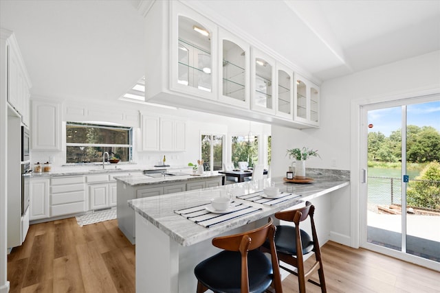 2949 Felstet Ln, Redding, CA 96001 - kitchen with glass insert cabinets, light wood-style floors, and white cabinets