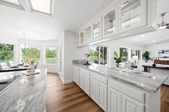 2949 Felstet Ln, Redding, CA 96001 - kitchen featuring light wood finished floors, white cabinets, glass insert cabinets, light stone counters, and a peninsula