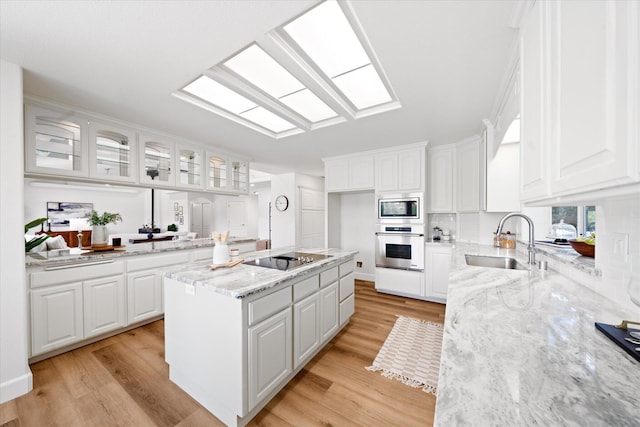 2949 Felstet Ln, Redding, CA 96001 - kitchen with appliances with stainless steel finishes, glass insert cabinets, white cabinetry, light stone countertops, and light wood-type flooring